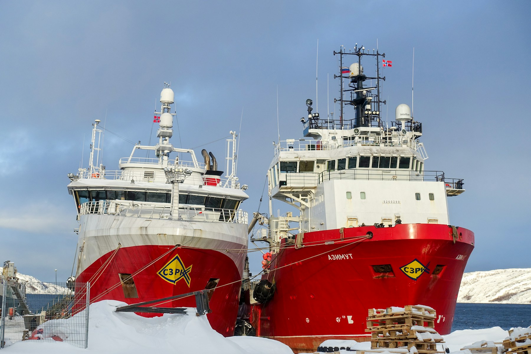 Rote Fischtrawler im verschneiten Hafen von Kirkenes