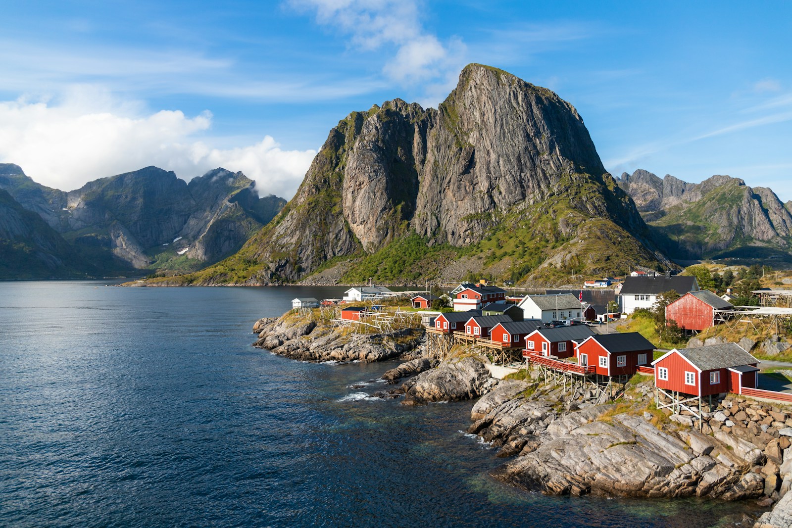 Rote Fischerhäuser in Hamnøy auf den Lofoten vor steilen Bergen